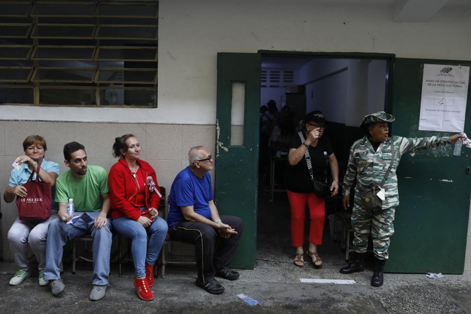 A pro-government militia member directs a voter at a voting center during a rehearsal for the July 28 presidential election, in Caracas, Venezuela, Sunday, June 30, 2024. (AP Photo/Cristian Hernandez Fortune)