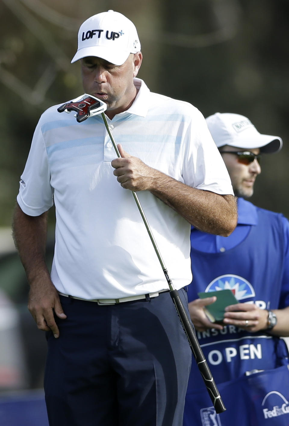 Stewart Cink, left, blows on his putter before sinking a putt for birdie as caddie Matt Hall, right, waits on the 17th hole of the North Course during the first round of the Farmers Insurance Open golf tournament Thursday, Jan. 23, 2014, in San Diego. (AP Photo/Gregory Bull)