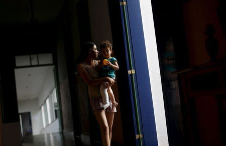 Eliene Almeida, head teacher at the municipal school in Bento Rodrigues district, witch was covered with mud after a dam, owned by Vale SA and BHP Billiton Ltd burst, carries her kid at a hotel housing the people displaced from the village, in Mariana, Brazil, November 9, 2015. The first Eliene Almeida, head teacher at the municipal school in Bento Rodrigues, knew of the deadly mud flow that destroyed her village was a cry from her husband. Most villagers were running for higher ground after hearing a dam at the local Samarco mine had burst, but no one inside the packed school was aware that a 20 meter-(65-foot)- high wall of mud and water was approaching. Almeida's husband raced to the school and sounded the warning. "He came in shouting that we had to run," Almeida, 31, told Reuters at a hotel housing the village's survivors. Frantically, she rounded up the children, aged mainly between 11 and 16. "Within three minutes everyone was out." The flood killed at least four people and on Monday -- four days after the disaster struck -- 25 people were still missing. But Almeida's 58 students all survived. REUTERS/Ricardo Moraes