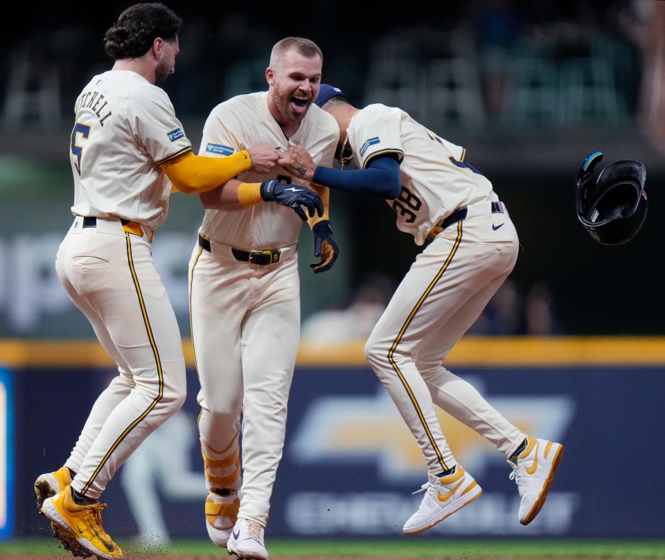 Designated hitter Jake Bauers celebrates with teammates Garrett Mitchell (5) and Devin Williams after his single in the ninth inning gave the Brewers a 2-1 victory over the Phillies.