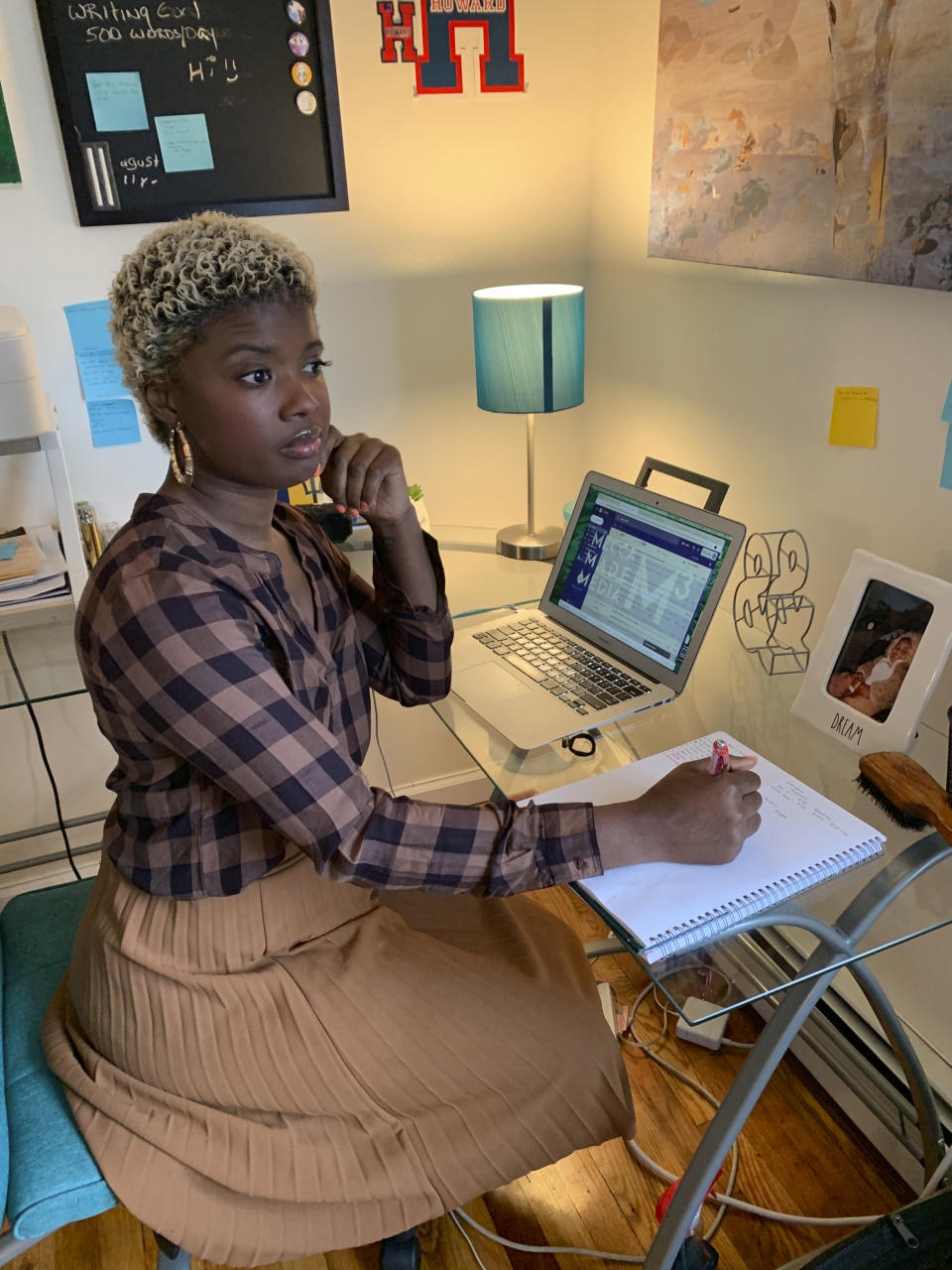 This Friday, April 3, 2020 photo shows Kasey Woods working from her home in Mount Vernon, N.Y. Woods, a New York mother of three who works in public relations, alternates her anxiety about the pandemic with feelings of pride for her oldest son, who's been accepted for the fall to Howard University. (Treylin Lewis via AP)