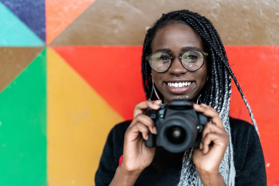 Person holding a camera and smiling.