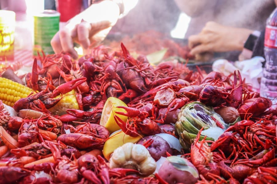 Pile of crawfish and carrots and vegetables on red checked table