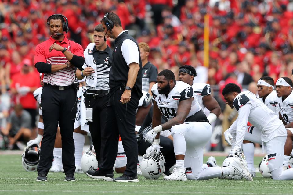 Cincinnati Bearcats defensive coordinator Marcus Freeman, left, stands next to head coach Luke Fickell during an injury timeout of a college football game against the Ohio State Buckeyes, Saturday, Sept. 7, 2019, at Ohio Stadium in Columbus. 