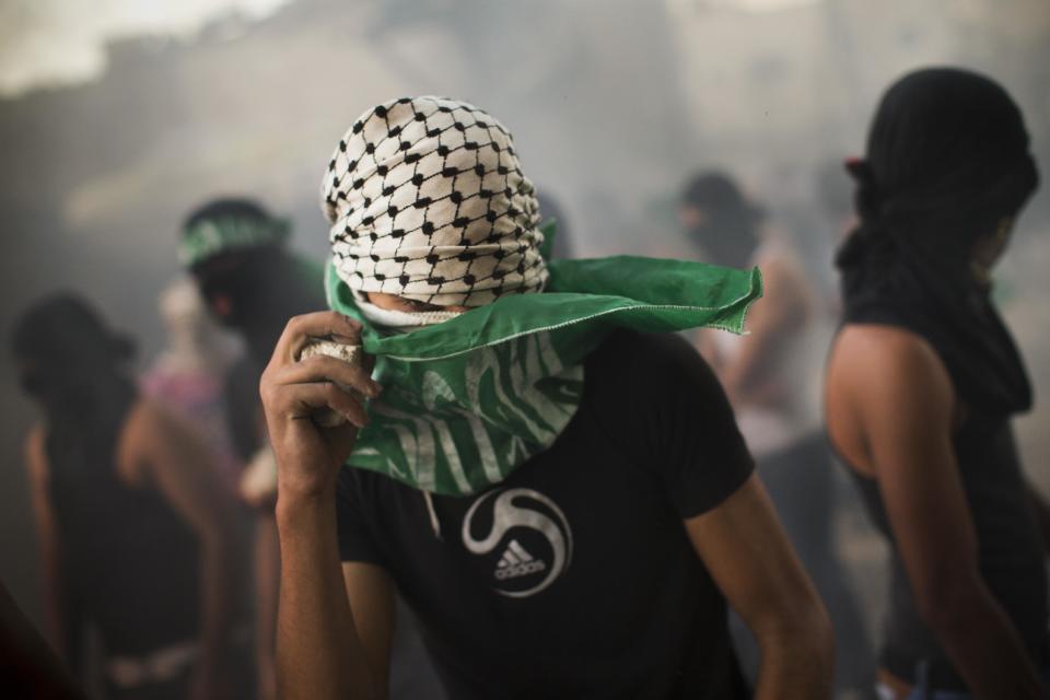 A masked Palestinian adjusts his Islamic flag during clashes with Israeli security forces, not pictured, in Shuafat refugee camp, Jerusalem, Tuesday, Sept. 18, 2012. Clashes erupted after a demonstration against an anti-Islam film called "Innocence of Muslims" that ridicules Islam's Prophet Muhammad. (AP Photo/Bernat Armangue)