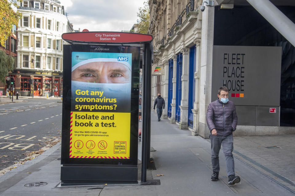 A man wearing a face mask as a precaution walking past a bus stop on an electronic display showing the NHS poster giving advice about the coronavirus testing in London. (Photo by Dave Rushen / SOPA Images/Sipa USA)