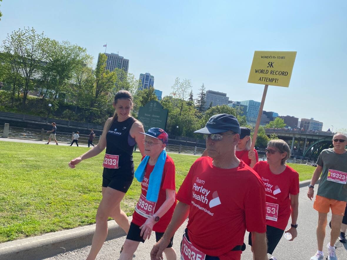 Réjeanne Fairhead, second from left, walks with her team of supporters Saturday. The 96-year-old Fairhead's time of 51:09.01 in the 5k race set a new world record in the women's 95-99 age category.  (Sannah Choi/CBC - image credit)