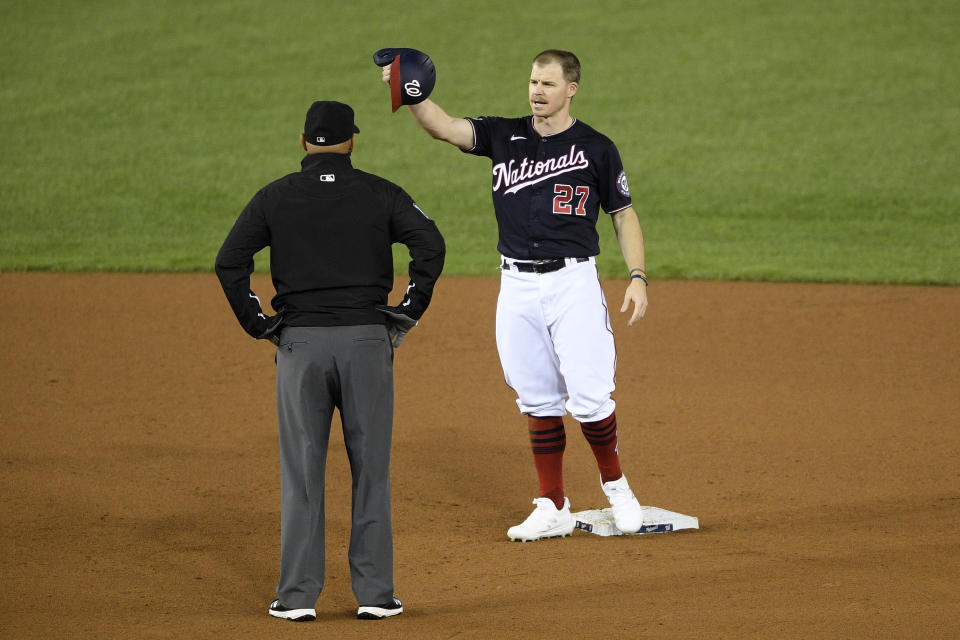 Washington Nationals' Brock Holt stands at second as he talks with second base umpire Vic Carapazza during a pitching change in the seventh inning of a baseball game against the Philadelphia Phillies, Monday, Sept. 21, 2020, in Washington. (AP Photo/Nick Wass)