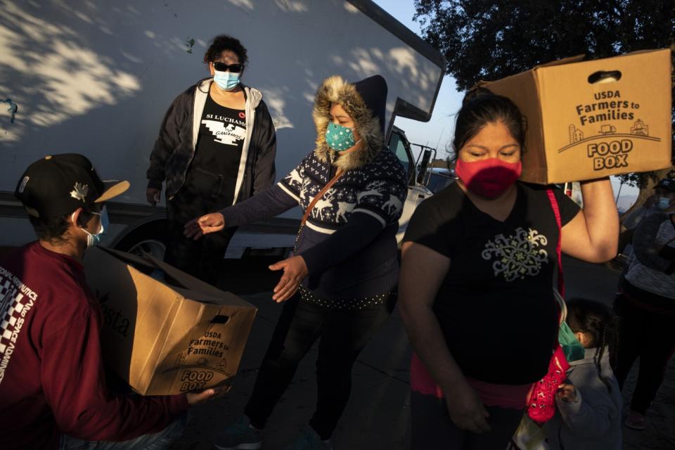 Women are handed cardboard cartons that say "Food Box."