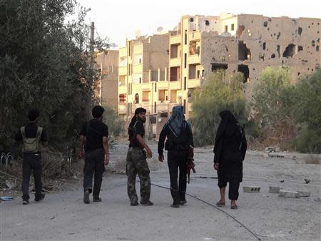 Free Syrian Army fighters walk on a damaged street in Deir al-Zor September 14, 2013. REUTERS/Mohamad Alderi