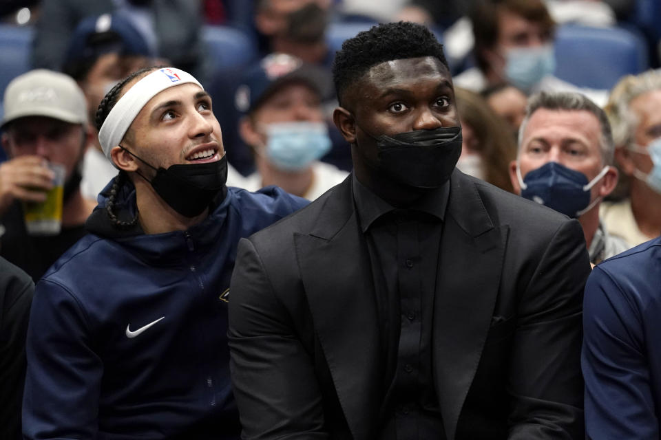 New Orleans Pelicans forward Zion Williamson, right, sits on the bench in street clothes with guard Jose Alvarado in the second half of an NBA basketball game against the Philadelphia 76ers in New Orleans, Wednesday, Oct. 20, 2021. The 76ers won 117-97. (AP Photo/Gerald Herbert)