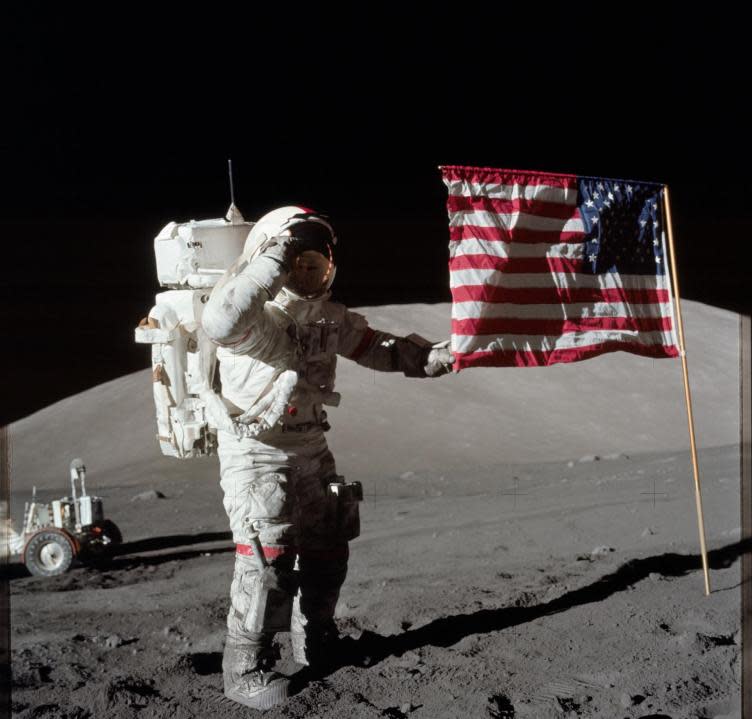 (Dec. 1972) — Astronaut Eugene A. Cernan, Apollo 17 commander, is photographed next to the deployed United States flag during lunar surface extravehicular activity (EVA) at the Taurus-Littrow landing site. The highest part of the flag appears to point toward our planet Earth in the distant background. (NASA)