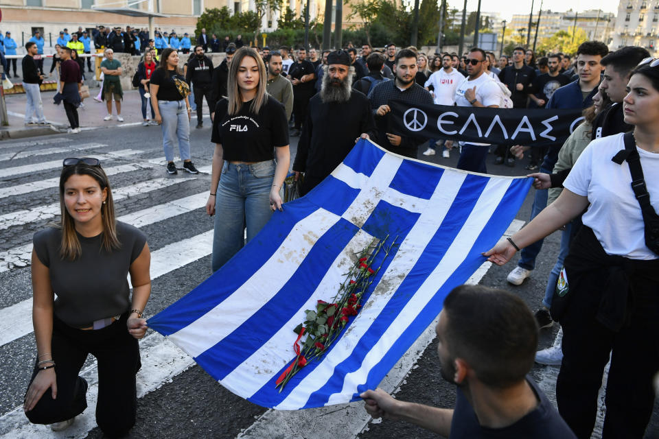 University students chant slogans as they hold a blood-stained Greek flag from the deadly 1973 student uprising during a rally in Athens, Friday, Nov. 17, 2023. Thousands of people are marching through central Athens to mark the 50th anniversary of a pro-democracy student uprising that was violently put down by the military dictatorship ruling Greece in 1973. (AP Photo/Michael Varaklas)