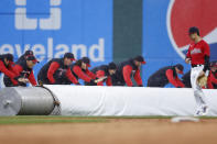 The Cleveland Guardians grounds crew rolls out the tarp as left fielder Steven Kwan walks to the dugout during a rain delay in the second inning of a baseball game against the Tampa Bay Rays, Tuesday, Sept. 27, 2022, in Cleveland. (AP Photo/Ron Schwane)