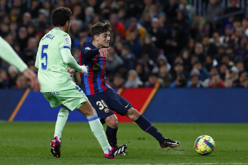 Gavi (derecha) del Barcelona intenta rematar a puerta frente a Luis Milla del Getafe en el partido de la Liga española, el domingo 22 de enero de 2023. (AP Foto/Joan Monfort)