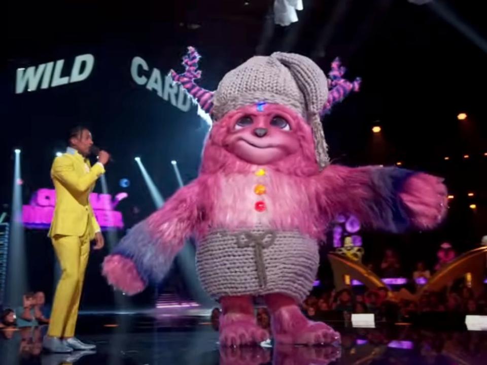 Nick Cannon stands next to a large costumed person on "The Masked Singer" season 10.