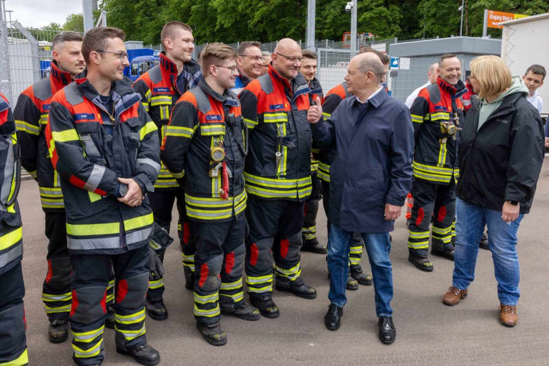 German Chancellor Olaf Scholz (C) visits with Anke Rehlinger, Saarland Minister-President, the Saarbruecken stadium with emergency personnel who were deployed as relief workers at the Saar floods. Helmut Fricke/dpa