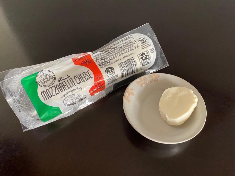 A log of Emporium Selection mozzarella with a slice of cheese on a plate next to it