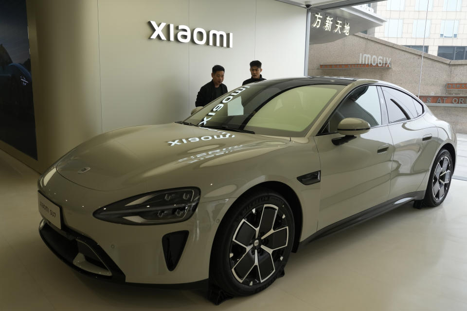 Visitors to the Xiaomi Automobile flagship store look at the Xiaomi SU7 electric car on display in Beijing, Tuesday, March 26, 2024. Xiaomi, a well-known smart consumer electronics brand in China, is joining the country's booming but crowded market for electric cars. (AP Photo/Ng Han Guan)