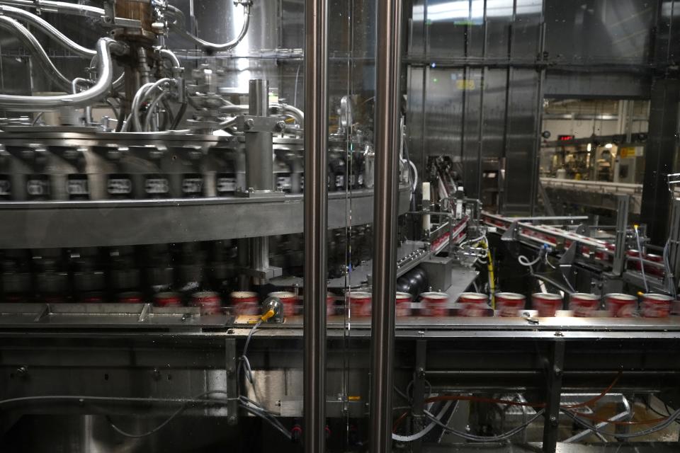 Coca-Cola cans move down a conveyer belt in the Swire Coca-Cola bottling plant Oct. 20, 2023, in Denver. Major corporations in water-guzzling industries such as apparel, food and beverage, and tech want to be better stewards of the freshwater resources they use. Coca-Cola said its water use in 2022 was about 10% more efficient compared to 2015. (AP Photo/Brittany Peterson)