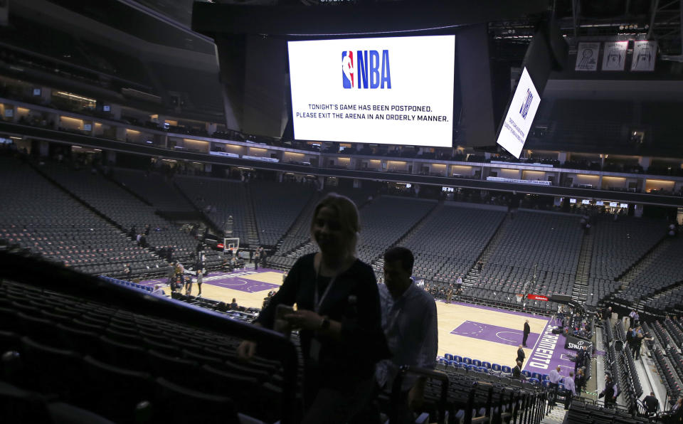 FILE - In this March 11, 2020, file photo, fans leave the Golden 1 Center after the NBA basketball game between the New Orleans Pelicans and Sacramento Kings in Sacramento, Calif., was postponed at the last minute due to the coronavirus. A year after the worldwide coronavirus pandemic stopped all the games in their tracks, the aftershocks are still being felt across every sector. (AP Photo/Rich Pedroncelli, File)