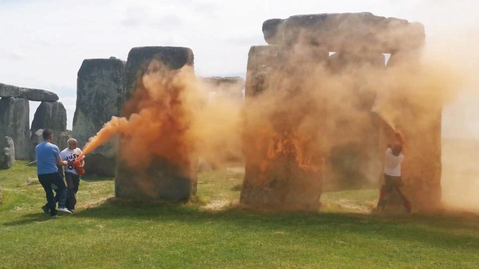 Two people in Just Stop Oil T-shirts, named by the group as Rajan Naidu, 73, and Niamh Lynch, 21, spray the ancient structure with canisters of orange powder paint (Just Stop Oil/PA Wire)