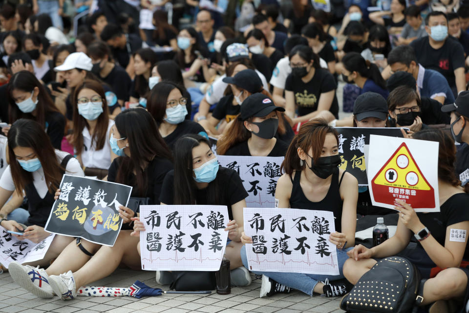 Workers from the medical and health care sector hold up signs that reads: "Citizens won't leave, medics won't abandon" during a demonstration in Hong Kong Friday, Aug. 2, 2019. Protesters plan to return to the streets again this weekend, angered by the government's refusal to answer their demands, violent tactics used by police - possibly in coordination with organized crime figures. (AP Photo/Vincent Thian)