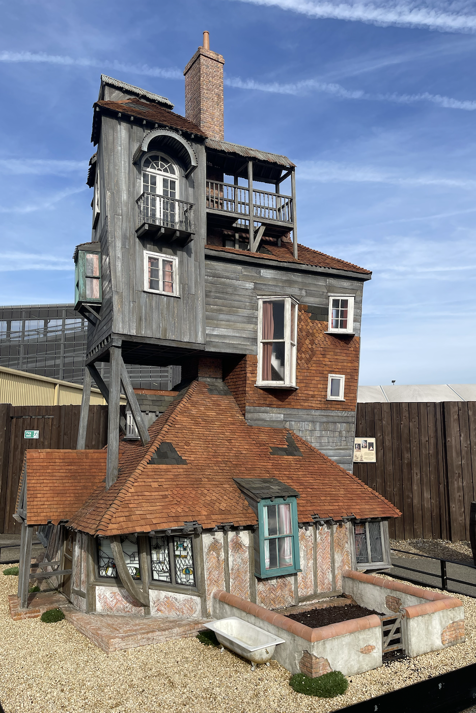 A quirky building sculpture with stacked, whimsical houses leaning precariously