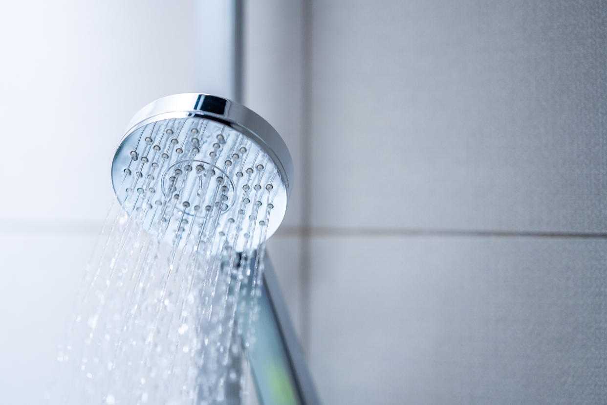 Low angle view of water flowing from shower head in bathroom.