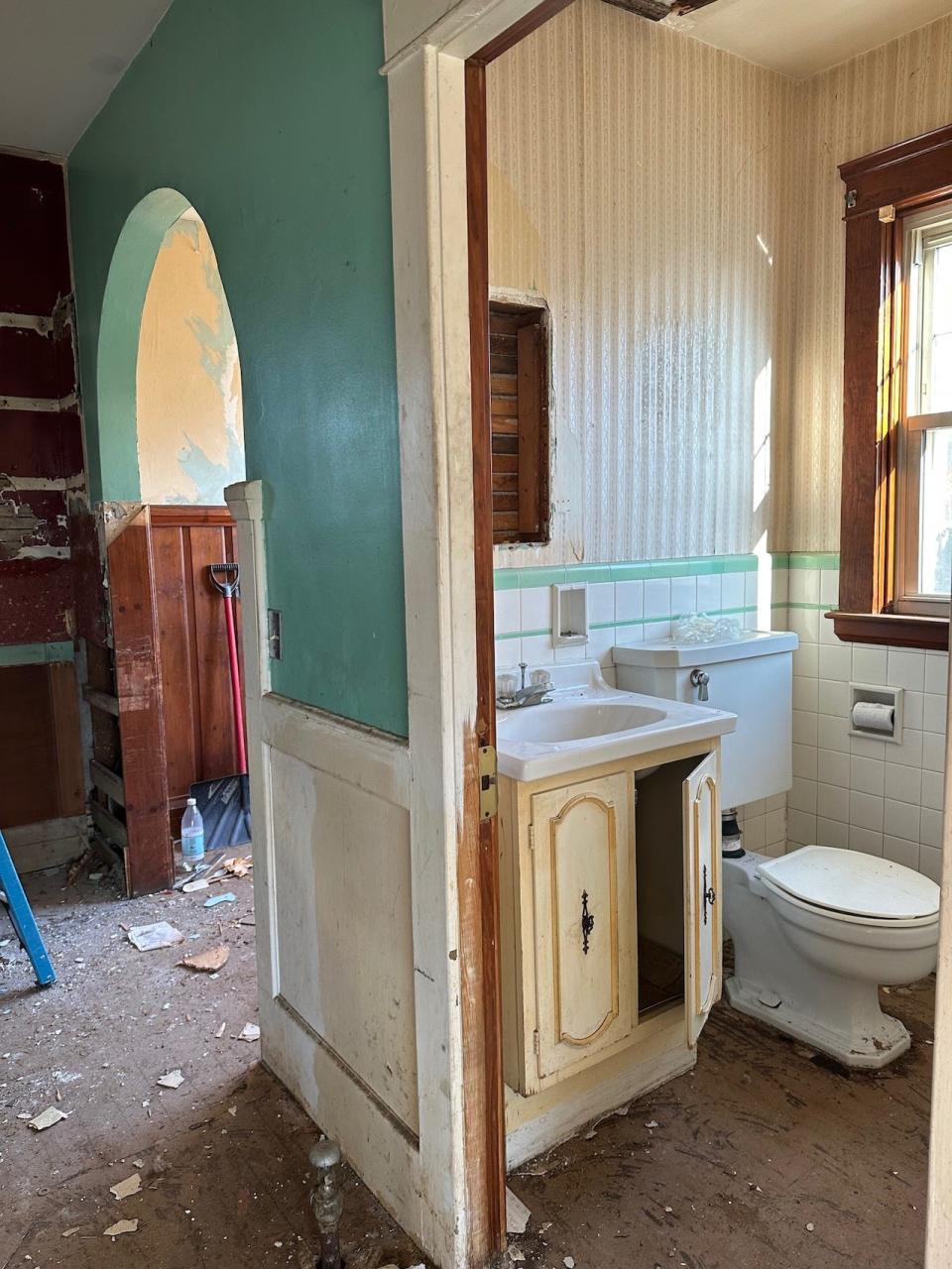 A bathroom in a cottage during construction with bits of dirty and dust lining the floor.