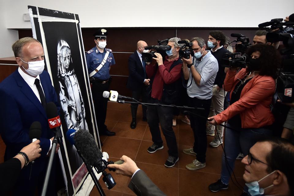 The senior French liaison officer Major Christophe Cengig (L) adresses the press near a piece of art attributed to Banksy, that was stolen at the Bataclan in Paris in 2019, and found in Italy, ahead of a press conference in L'Aquila on June 11, 2020. - The work was found in an abandoned farmhouse in Abruzzo, l'Aquila prosecutor informed on June 10, 2020. (Photo by Filippo MONTEFORTE / AFP) / RESTRICTED TO EDITORIAL USE - MANDATORY MENTION OF THE ARTIST UPON PUBLICATION - TO ILLUSTRATE THE EVENT AS SPECIFIED IN THE CAPTION (Photo by FILIPPO MONTEFORTE/AFP via Getty Images)