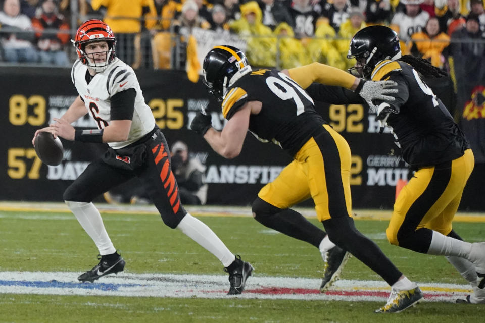 Cincinnati Bengals quarterback Jake Browning (6) scrambles and looks to pass as Pittsburgh Steelers linebacker T.J. Watt (90) and defensive tackle Armon Watts (94) try to stop him during the second half of an NFL football game, Saturday, Dec. 23, 2023, in Pittsburgh. (AP Photo/Gene J. Puskar)