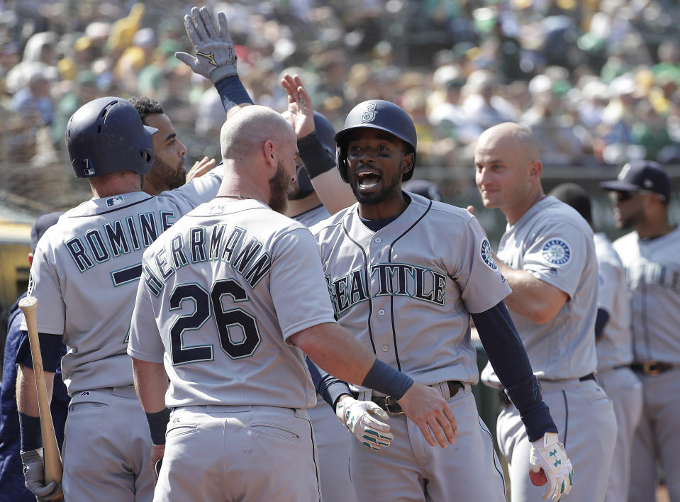 Seattle Mariners' Dee Gordon, center right, is congratulated by teammates after hitting a two-run home run against the Oakland Athletics during the 12th inning of a baseball game in Oakland, Calif., Wednesday, Aug. 15, 2018. (AP Photo/Jeff Chiu)