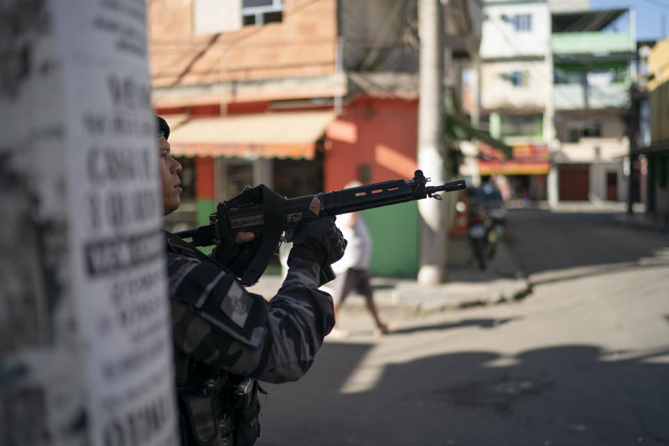 In this July 31, 2019 photo, a police officer aims his weapon during an operation at the Mare complex slum in Rio de Janeiro, Brazil. Many Brazilians see police-caused deaths as a regrettable but acceptable price for cracking down on the country's rampant crime problem. (AP Photo/Leo Correa)