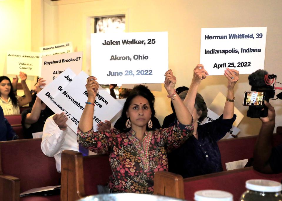 Attendees at a memorial ceremony Saturday for two Black men who were lynched in Osteen in 1896 hold up signs bearing the names of other victims who died as a result of racial violence or excessive force.