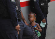 En esta imagen del 27 de mayo de 2019, agentes de inmigración y de la Policía Federal retienen a una niña después de que su madre intentara saltarse una fila en un centro de inmigración en Tapachula, en el estado mexicano de Chiapas. (AP Foto/Marco Ugarte)