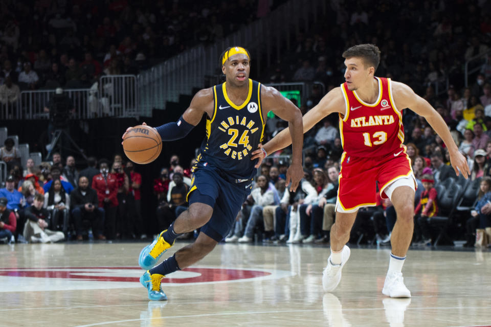 Indiana Pacers guard Buddy Hield (24) dribbles past Atlanta Hawks guard Bogdan Bogdanovic (13) during the second half of an NBA basketball game Sunday, March 13, 2022, in Atlanta. (AP Photo/Hakim Wright Sr.)