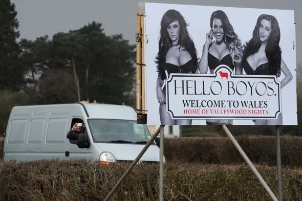 ***EXCLUSIVE - FREE FOR USE***ABERGAVENNY, UNITED KINGDOM - FEBRUARY 23: A van driver takes a picture of an MTV pop-up billboard depicting The Valley TV Reality Stars Natalee Harris, Lateysha Grace and Jenna Jonathan on February 23, 2014 in Abergavenny, Wales.A CHEEKY alternative ëWelcome to Walesí sign on the A465 Welsh border has been setting male commuterís hearts racing. The pop-up billboard, which was installed on Sunday morning (Feb 23), carries the phrase 'Hello Boyos' - a cheeky nod to the iconic Wonderbra ads of the mid 90s. Erected by MTV bosses to celebrate the third season of reality TV show The Valleys, which hits TV screens on Tuesday night at 10pm on MTV, the eye-popping sign features three of the showís biggest stars Natalee Harris, Lateysha Grace and Jenna Jonathan in racy underwear.  The striking design is being trialled on the A465 on the Welsh border, but is due to be rolled out at several crossings into Wales later this week in advance of the new series airing.PHOTOGRAPH BY Dan Rowley / Barcroft MediaUK Office, London.T +44 845 370 2233W www.barcroftmedia.comUSA Office, New York City.T +1 212 796 2458W www.barcroftusa.comIndian Office, Delhi.T +91 11 4053 2429W www.barcroftindia.com