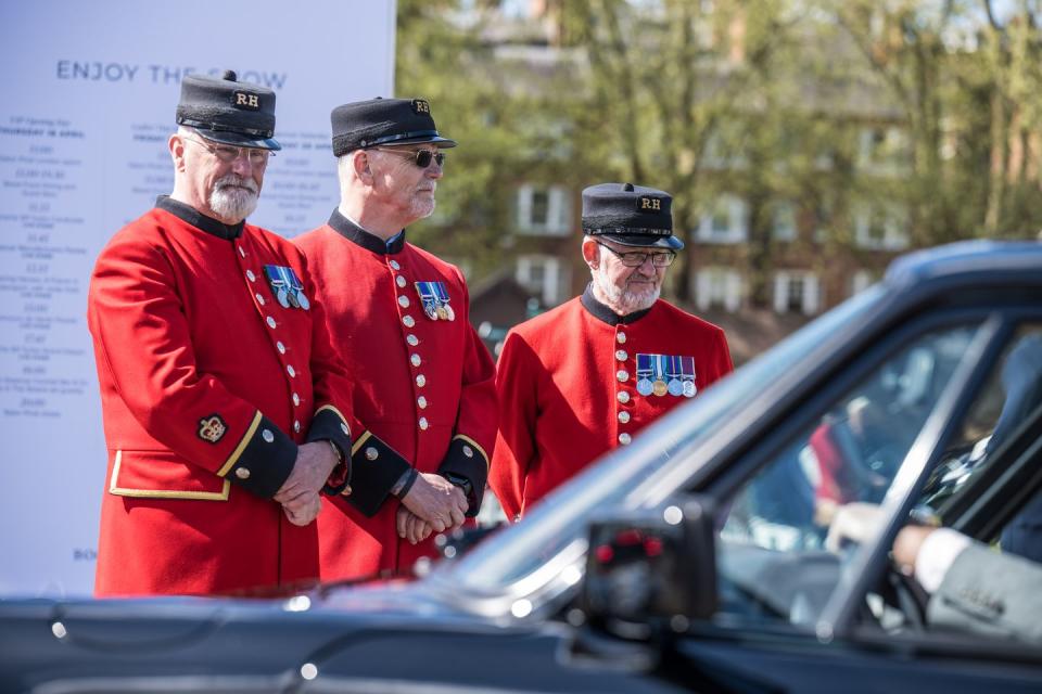 a group of men in uniform standing next to a car