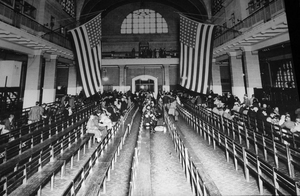 FILE - In this 1924 file photo, immigrants from Europe sit in the registry room at Ellis Island in New York harbor. Throughout history, the United States has used all sorts of physical or mental exams for immigrants seeking just to get into the country outside of becoming a citizen. (AP Photo/File)