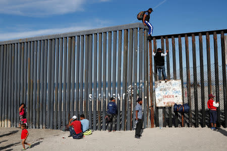 Migrants, part of a caravan of thousands trying to reach the U.S., look through the border fence between Mexico and the United States, in Tijuana, Mexico November 15, 2018. REUTERS/Carlos Garcia Rawlins