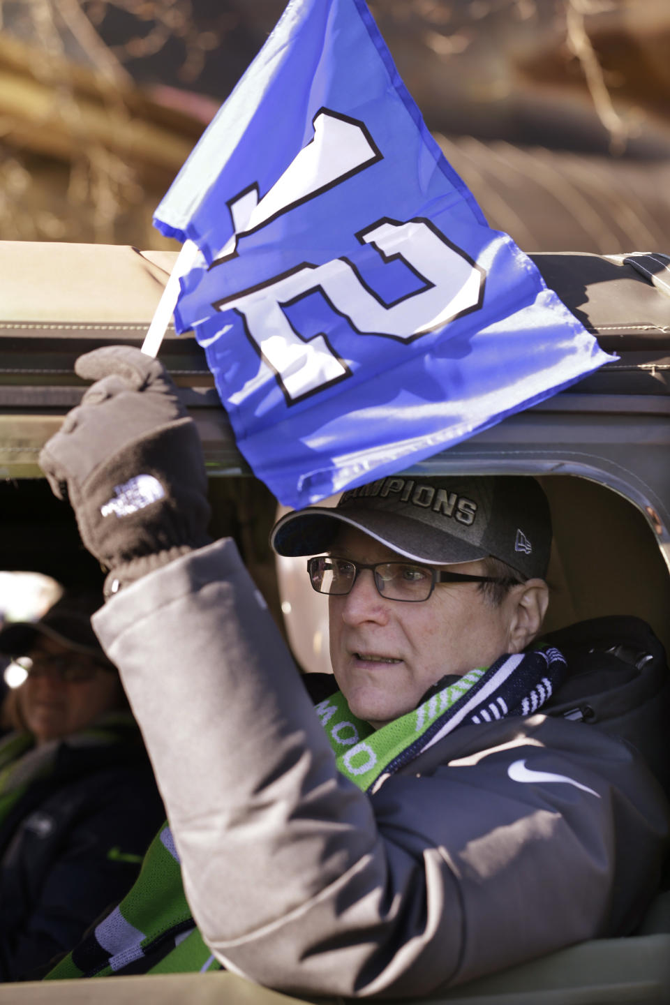 Seattle Seahawks owner Paul Allen waves a 12th Man flag out of his window as he rides in a parade for the NFL football Super Bowl champions Wednesday, Feb. 5, 2014, in Seattle. The Seahawks defeated the Denver Broncos 43-8 on Sunday. (AP Photo/Elaine Thompson)