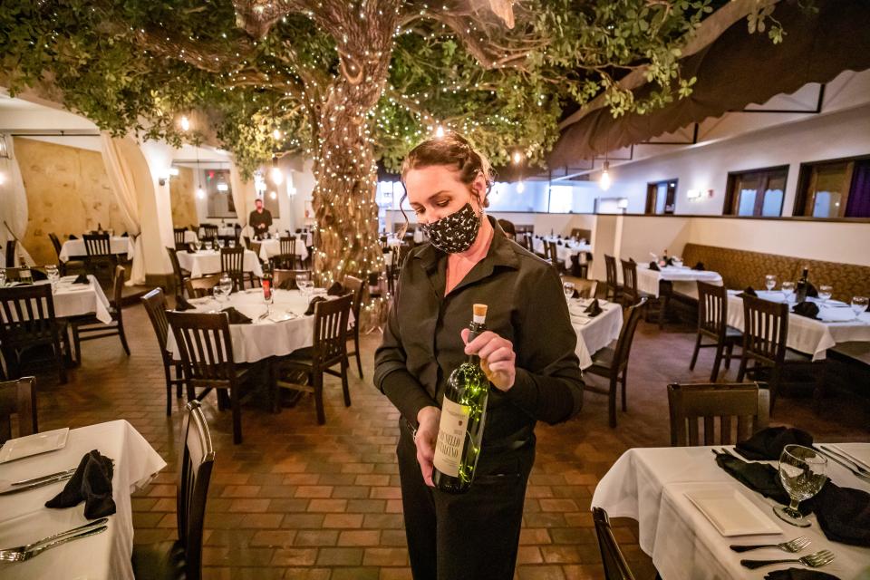 Server Chantille Gooding turns on lights inside a wine bottle as she preps tables at Firefly in September 2021. The fine-dining restaurant was listed in a recent blog by Visit Panama City Beach as being among the best places to eat in the Panama City Beach area.