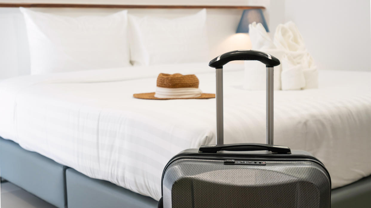  A suitcase in front of a mattress in a hotel room. 
