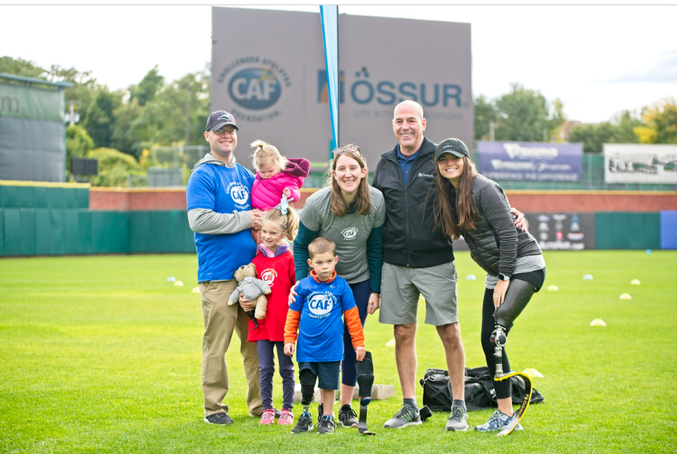 Three-year-old TJ DeAngelo, bottom center, poses for a photo with his parents and sisters at left; his prosthetist Scott Cummings, second from right; and Noelle Lambert, a para-athlete and founder of The Born to Run Foundation. On Oct. 2, he was given a Nike sports running blade during a mobility clinic put on by the Challenged Athletes Foundation.