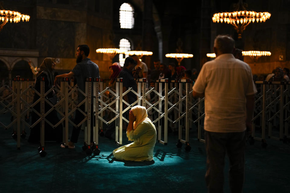 A Muslim worshipper prays out of the praying time as tourists and locals visit Byzantine-era Hagia Sophia mosque in Istanbul, Turkey, Wednesday, July 5, 2023. With tourism reaching or surpassing pre-pandemic levels across Southern Europe this summer, iconic sacred sites struggle to find ways to accommodate both the faithful who come to pray and millions of increasingly secular visitors attracted by art and architecture. (AP Photo/Francisco Seco)