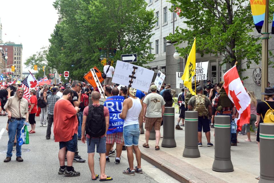 People gather holding upside down Canada flags and pro Trump flags outside the U.S. embassy in Ottawa.