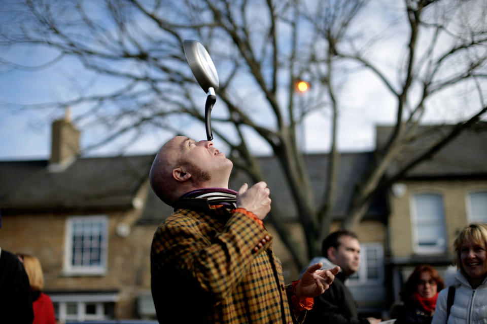 Performance artist The Great Gappo balances a frying pan on his nose as he entertains people before the start of the annual Shrove Tuesday trans-Atlantic pancake race in the town of Olney, in Buckinghamshire, England, Tuesday, March 4, 2014. Every year women clad in aprons and head scarves from Olney and the city of Liberal, in Kansas, USA, run their respective legs of the race with a pancake in their pan, flipping it at the beginning and end of the race. According to legend, the Olney race started in 1445 when a harried housewife arrived at church on Shrove Tuesday still clutching her frying pan with a pancake in it. Liberal challenged Olney to a friendly international competition in 1950 after seeing photos of the race in a magazine. (AP Photo/Matt Dunham)