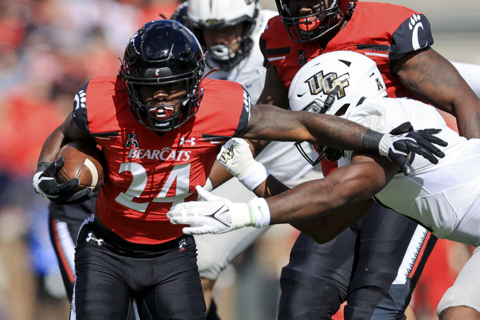 Cincinnati running back Jerome Ford (24) carries the ball as he breaks a tackle against UCF linebacker Jeremiah Jean-Baptiste, right, during the first half of an NCAA college football game, Saturday, Oct. 16, 2021, in Cincinnati. (AP Photo/Aaron Doster)