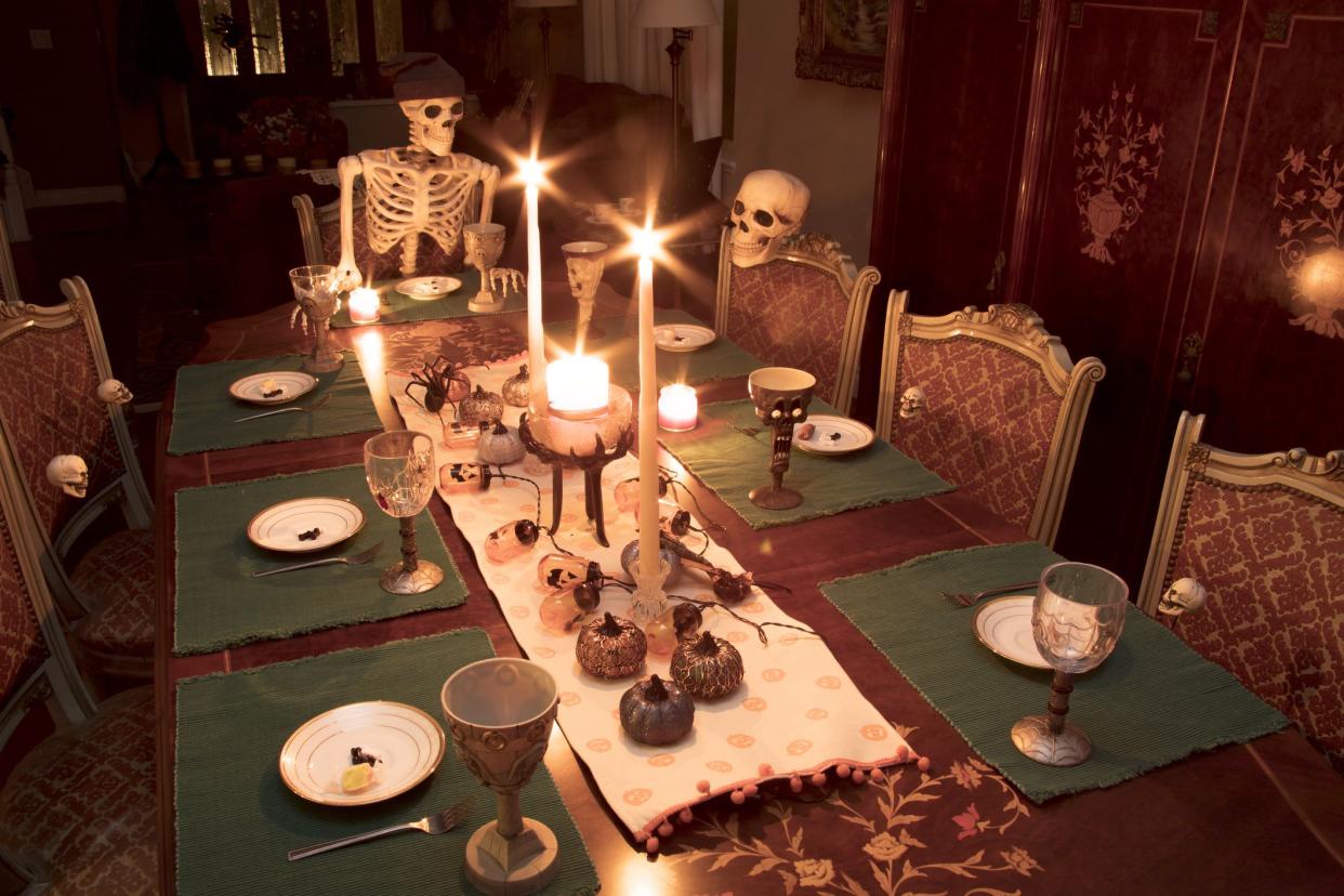 Skeleton family gathered for a Halloween dinner celebrating the holiday at a formal dining table